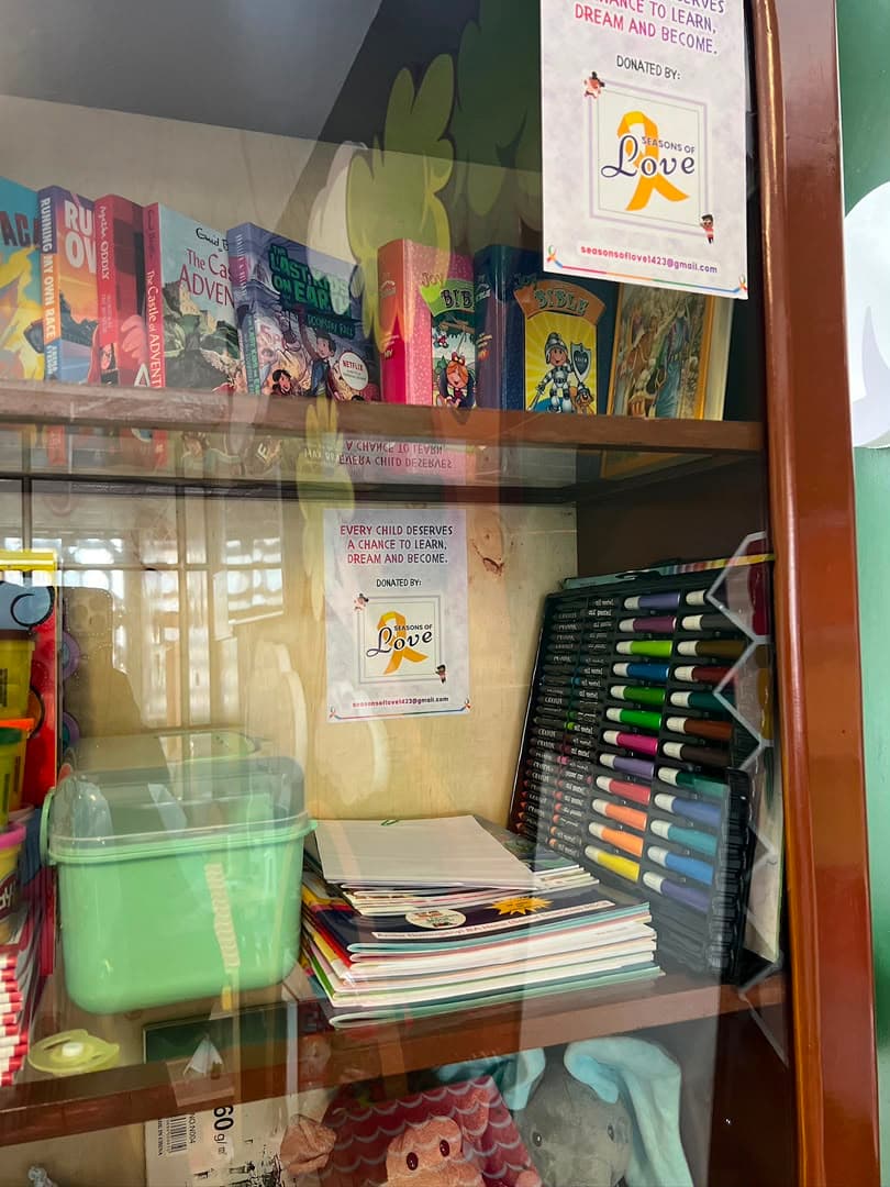 A ward shelf stocked with children’s books, notebooks and packs of colouring pens