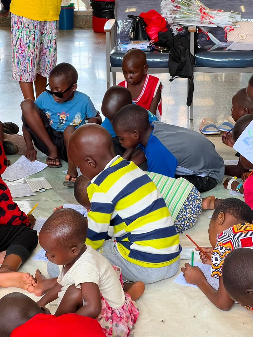 A group of children kneeling and lying on the floor, each colouring their own page