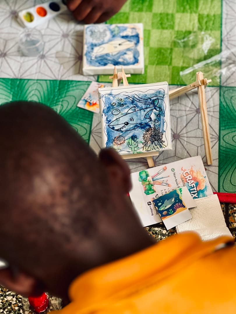 A child looking down at the underwater scene they have just painted on a mini canvas