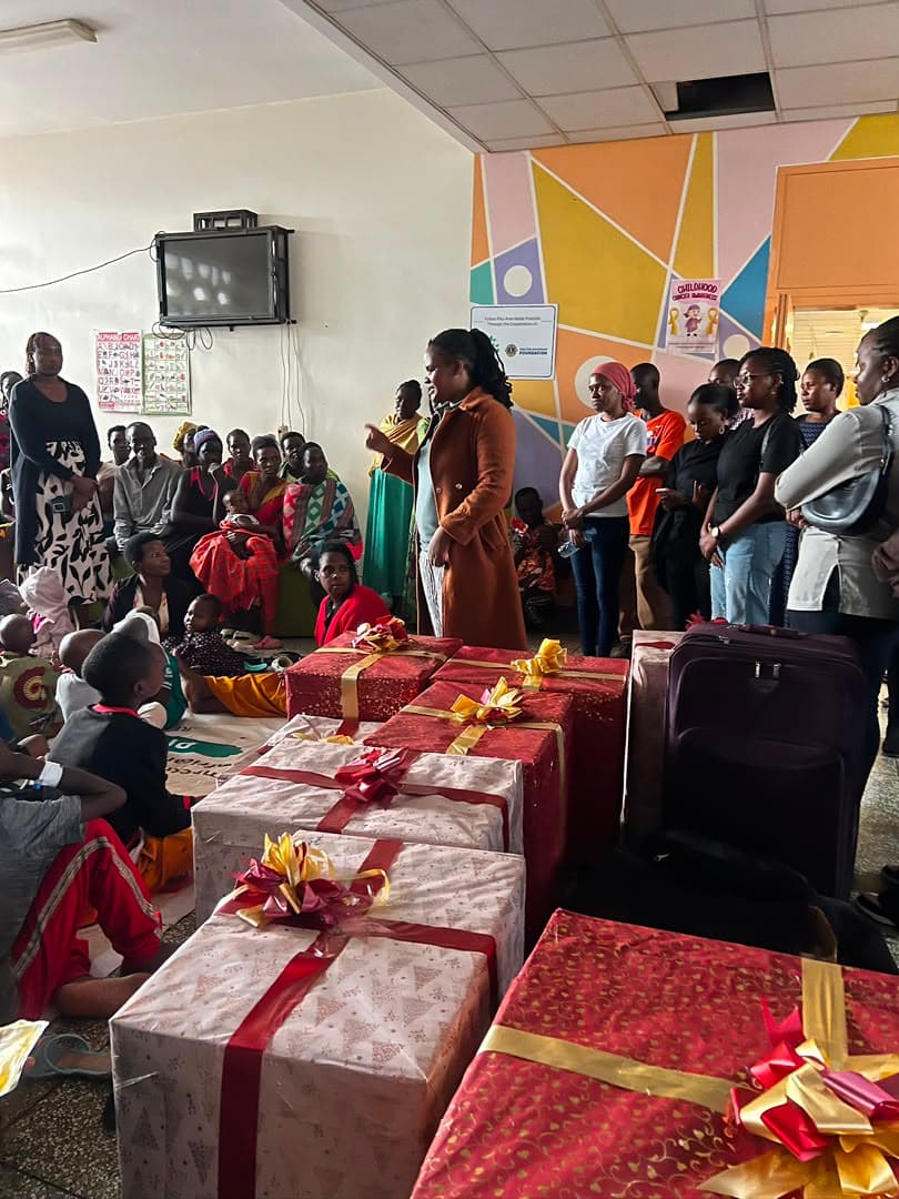 A room lined with wrapped gifts as a volunteer speaks to the families before the handover