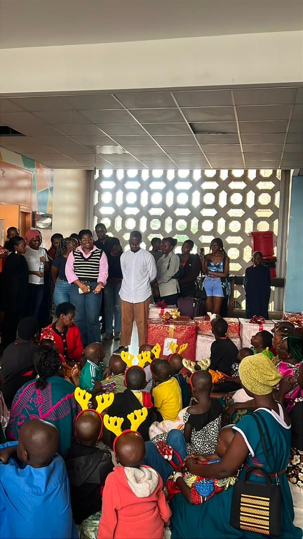 Volunteers standing to address a room full of caregivers and children on the ward