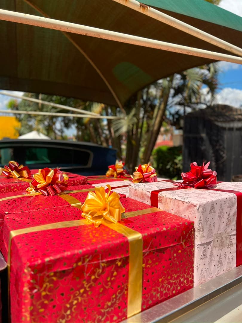 Presents in red and gold wrapping stacked in the open boot of a car