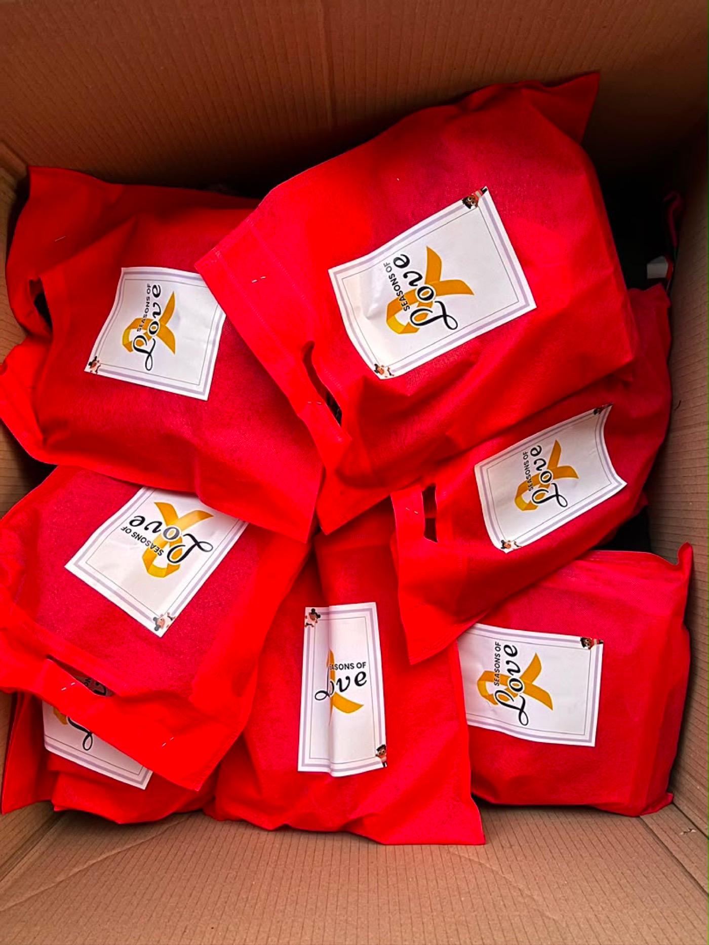 Red Seasons of Love gift bags packed into a box, ready for the ward